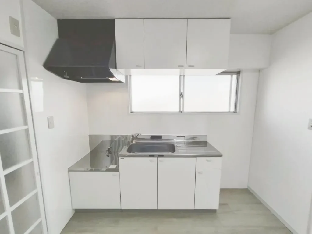 原状回復後の賃貸マンションキッチン。白い収納とステンレス天板の清潔な台所