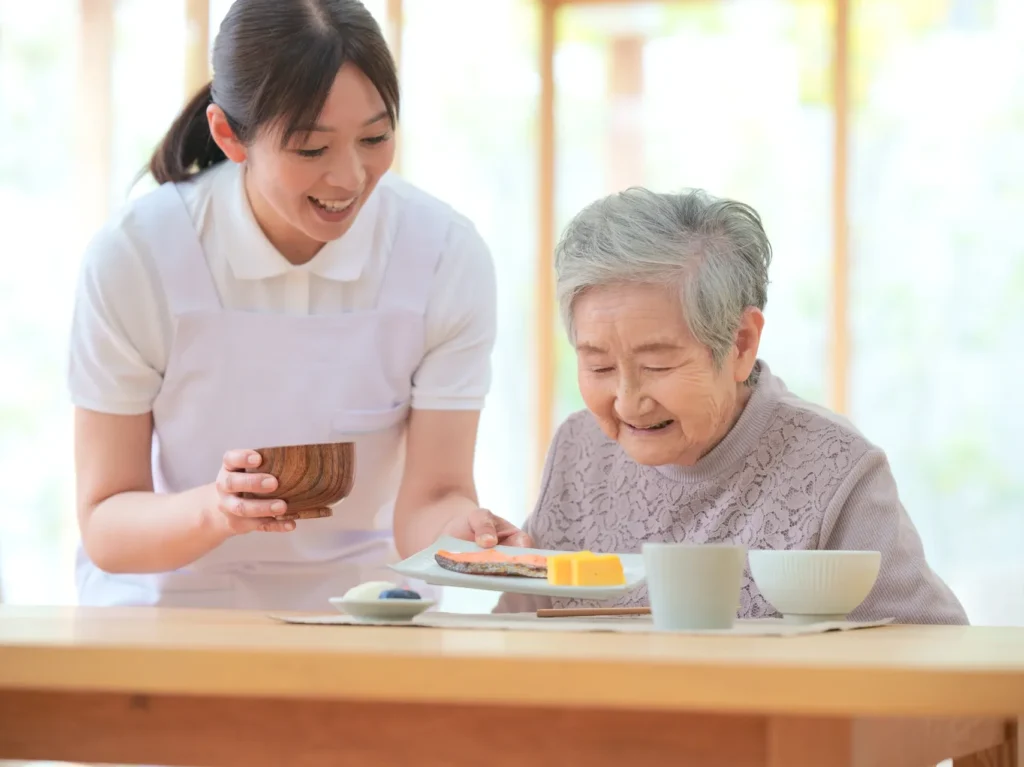 高齢者施設で介護スタッフが入居者をサポートする様子。住環境改善のイメージ