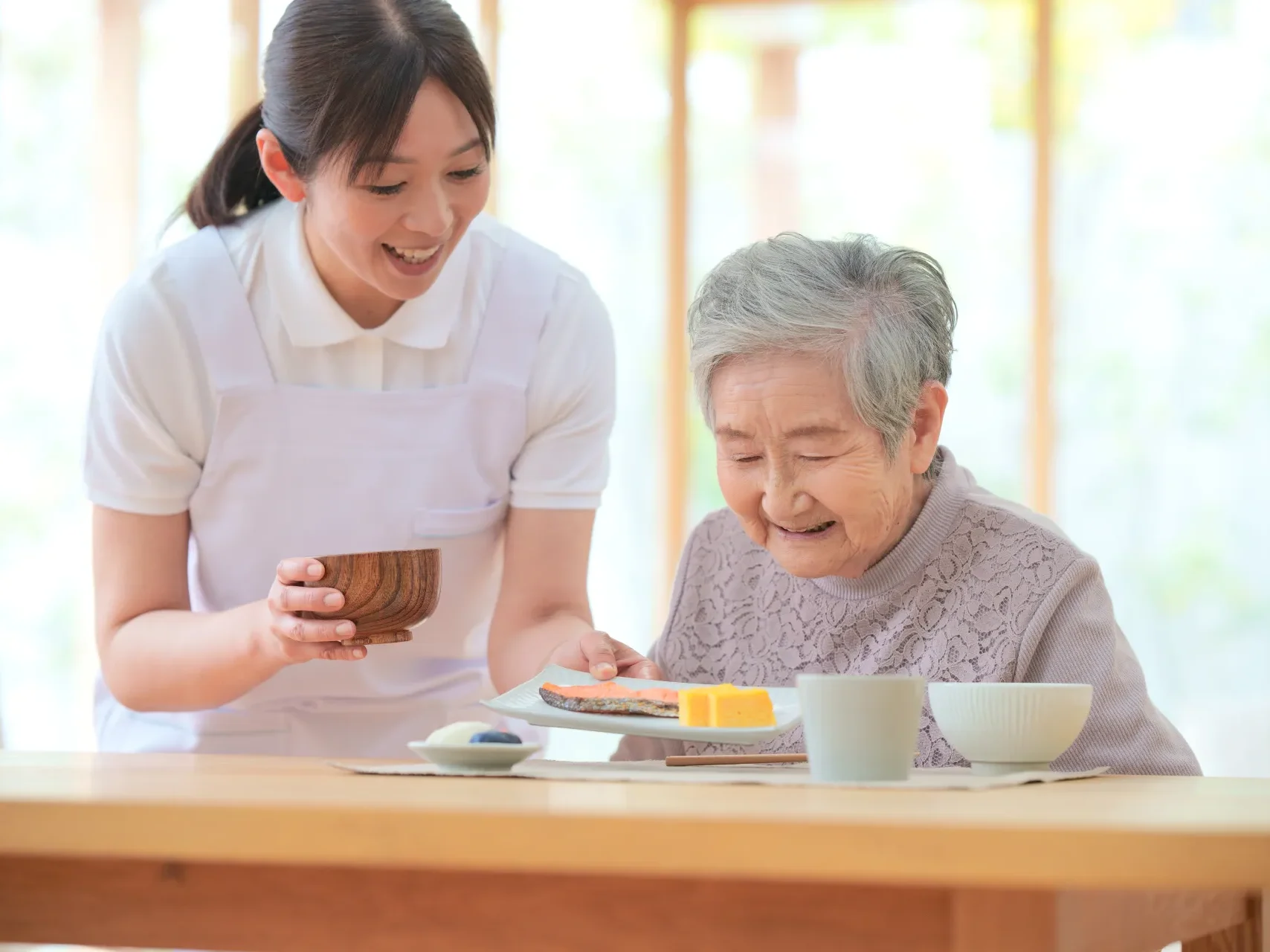 高齢者施設で介護スタッフが入居者をサポートする様子。住環境改善のイメージ