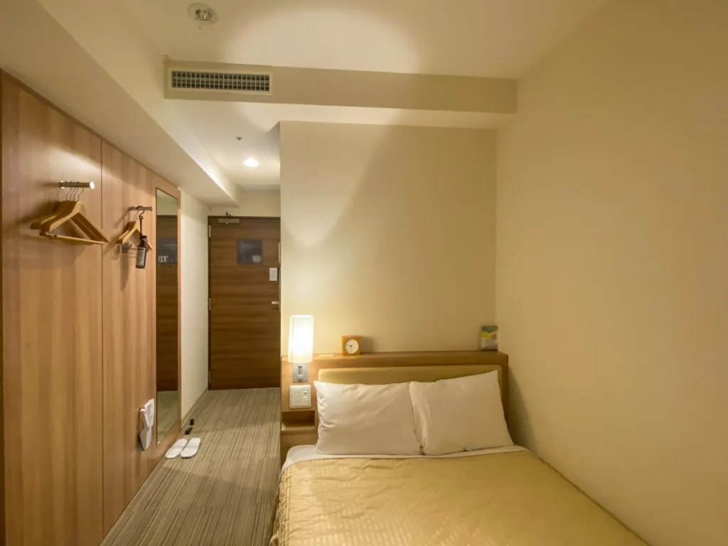 部分改修後のホテル客室。ベッドと木目調内装で落ち着いた空間