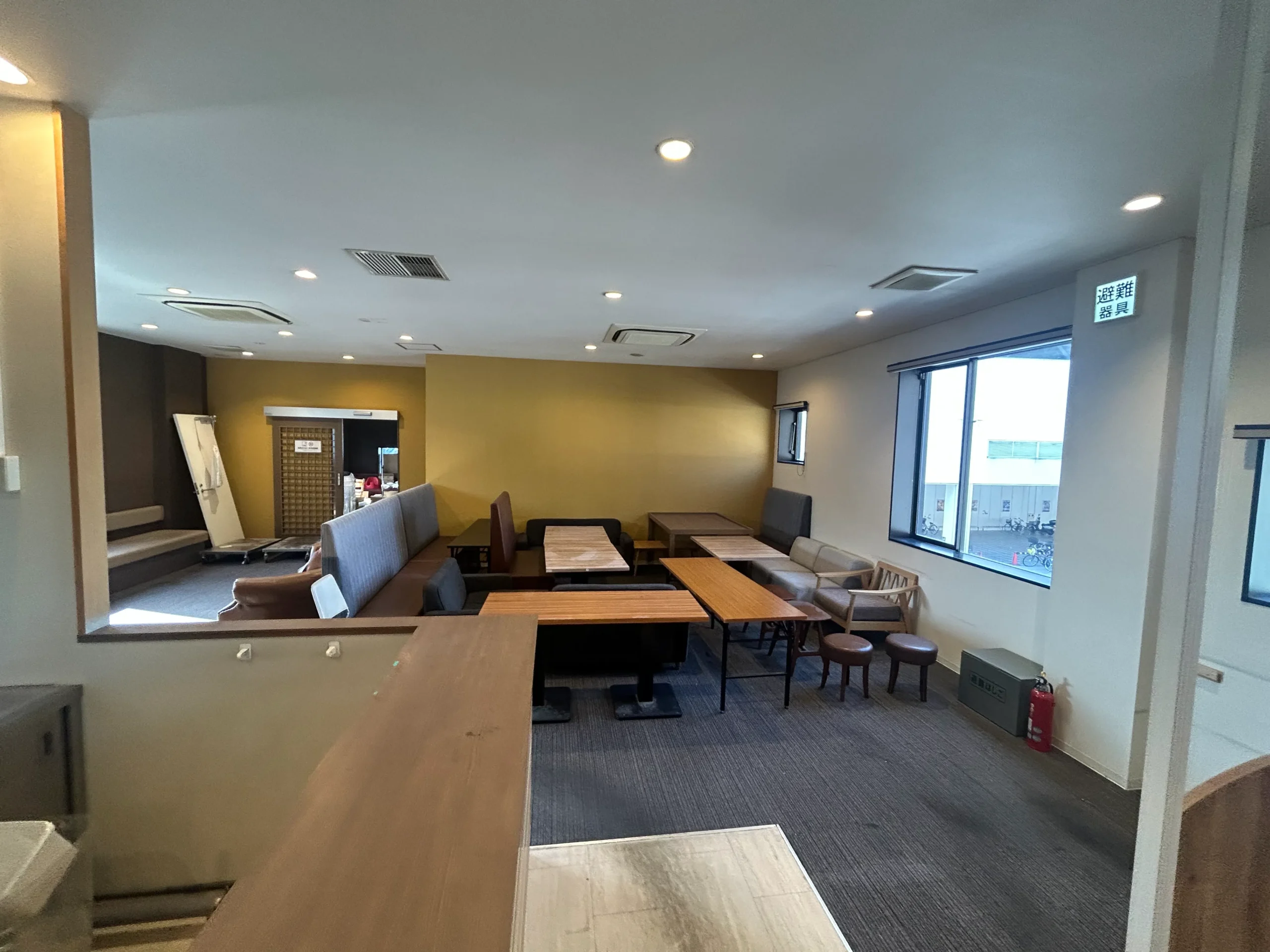 店舗内装リフォームの施工前写真。既存のテーブル・椅子・ベンチソファが残る改修前の店内全景