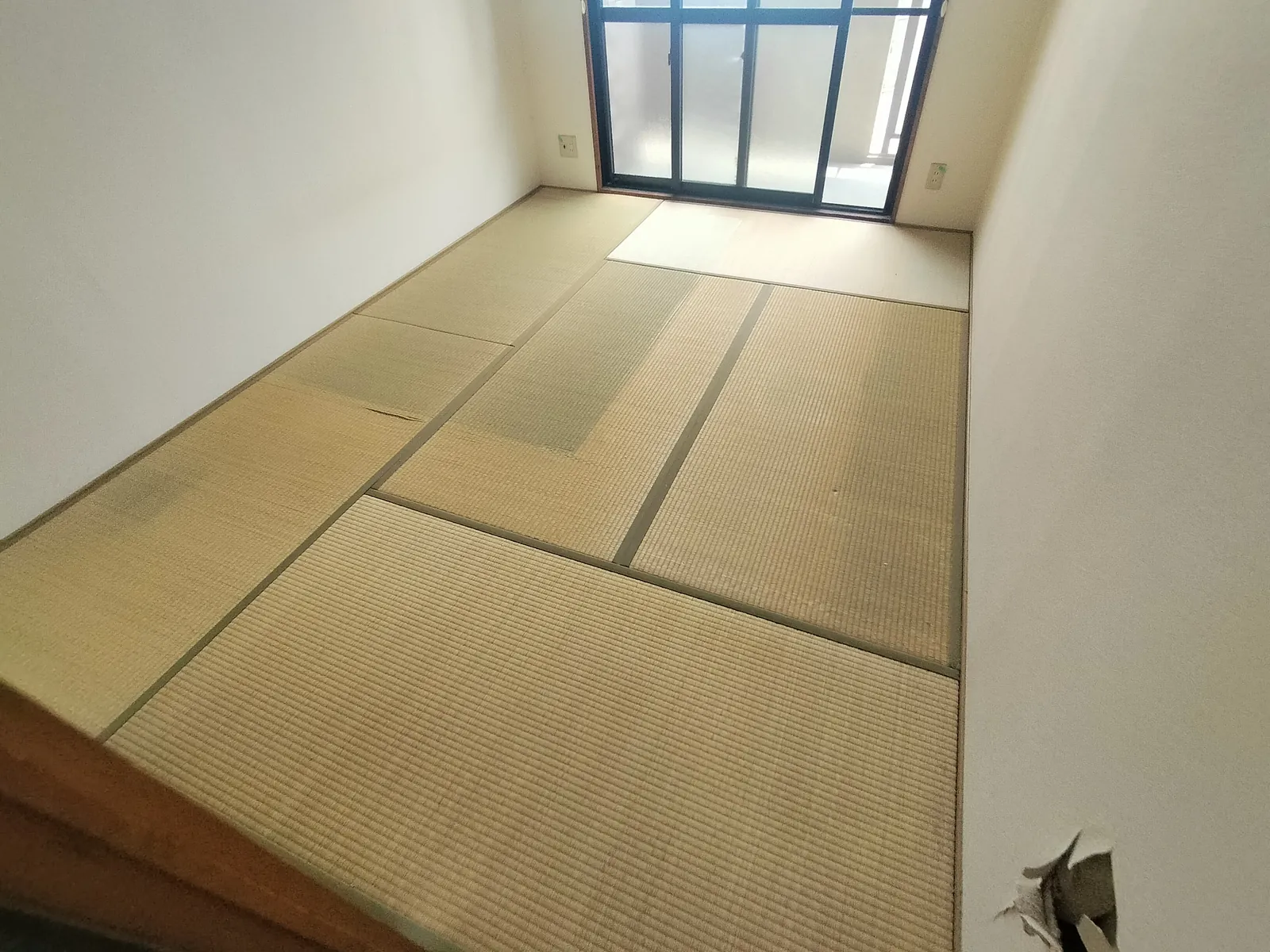 表替え前の和室。日焼けで変色した畳6枚と壁クロスの破れが残る状態