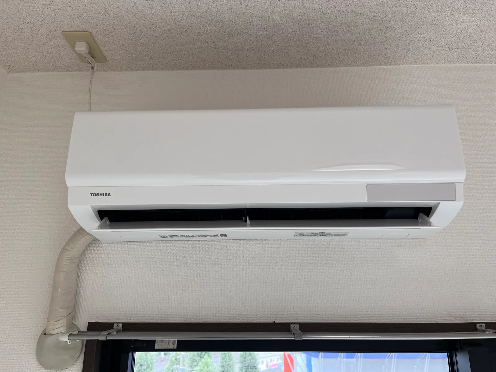 LDKの掃き出し窓の上に設置された壁掛けエアコンと配管カバー