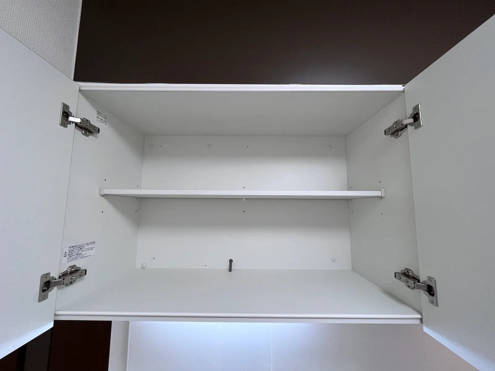 交換した新しいキッチンの吊戸棚を開けた内部。棚板付きの白い収納
